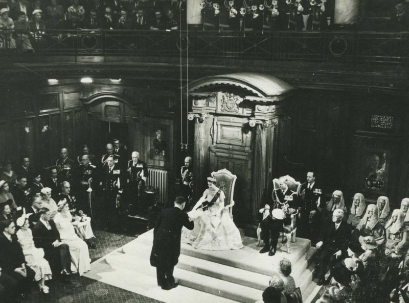 Prime Minister Sidney Holland hands the Queen her Speech from the Throne, with Prince Philip to her left
